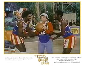 Two Harlem Globetrotters holding a basketball, standing on either side of Gilligan, who is dressed in his signature outfit and holding the ball nervously, in a scene from The Harlem Globetrotters on Gilligan’s Island.