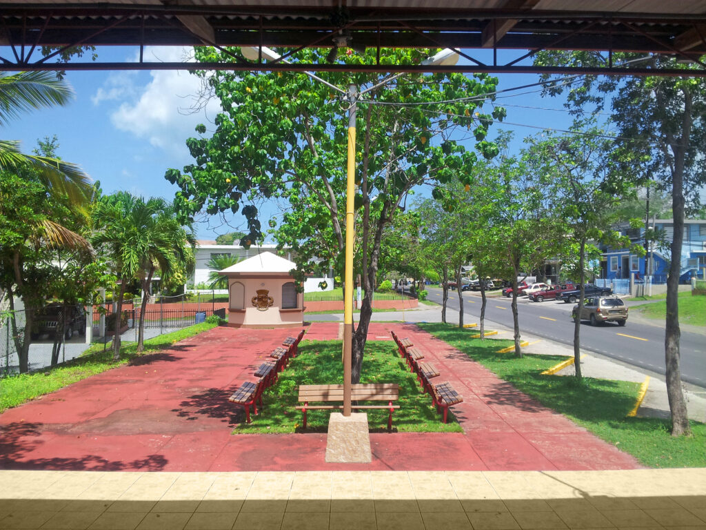 Plaza Cofresí in Boquerón, Cabo Rojo, Puerto Rico, featuring a red brick walkway, trees, benches, and a small pavilion dedicated to pirate Roberto Cofresí.