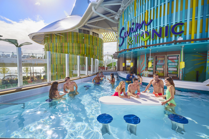 A modern cruise ship pool at Swim & Tonic on the Icon of the Seas, with people enjoying a swim-up bar, bright decor, and a lively, sunlit atmosphere perfect for socializing.