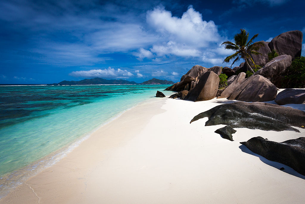 A view of Anse Source d’Argent beach with clear turquoise water, white sand, and large granite boulders.