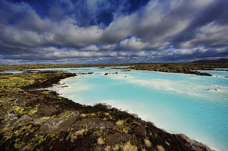 The Blue Lagoon in Iceland, with milky blue geothermal waters and rocky volcanic surroundings under a cloudy sky.