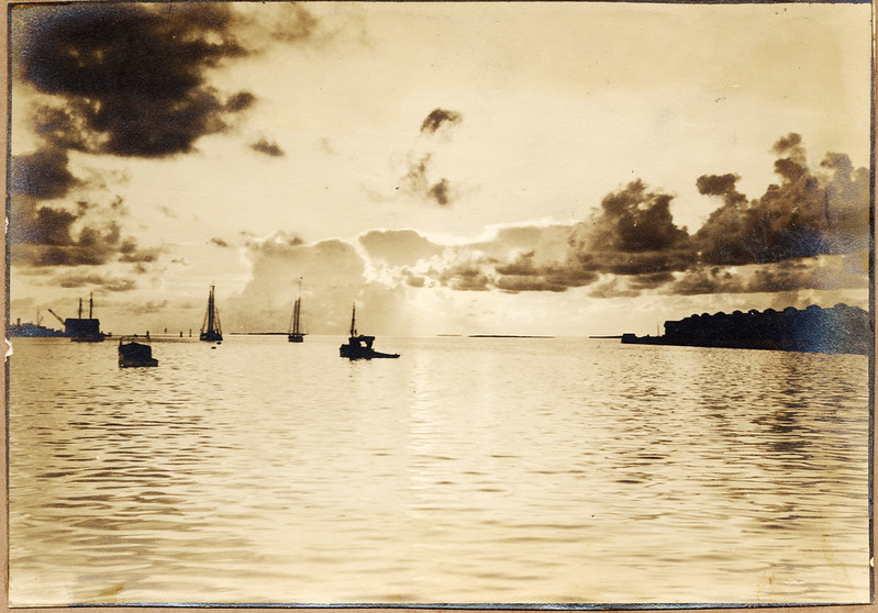 Sepia-toned photo of boats on calm water at sunrise or sunset in Key West, Florida, with clouds and the horizon in the background.