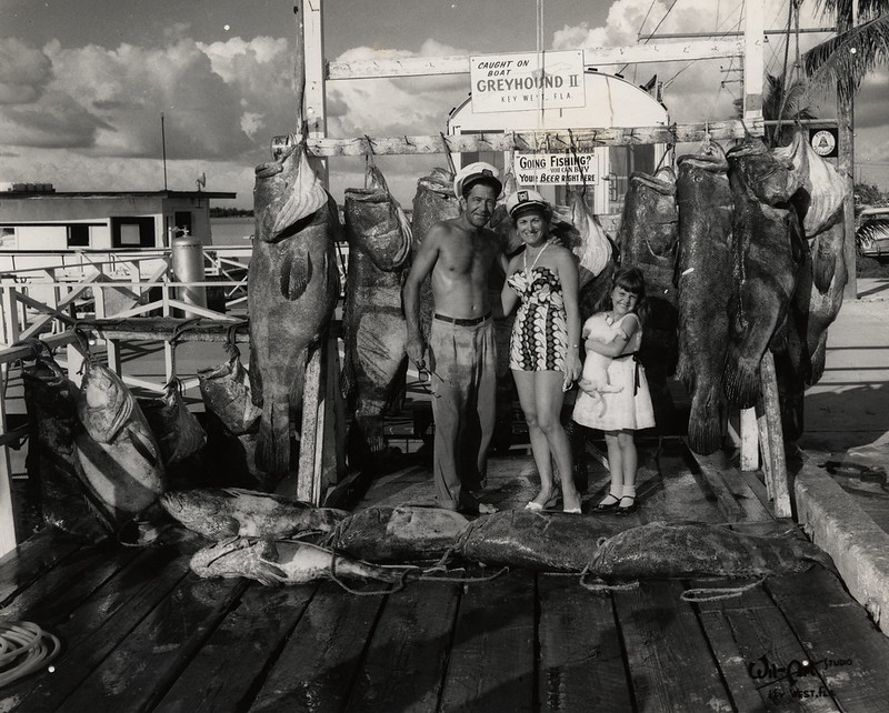 A black-and-white photo of Captain Tony Tarracino, possibly with family or friends, standing on a dock in Key West surrounded by a large catch of fish, reflecting his adventurous life and connection to Jimmy Buffett’s “Last Mango in Paris.”