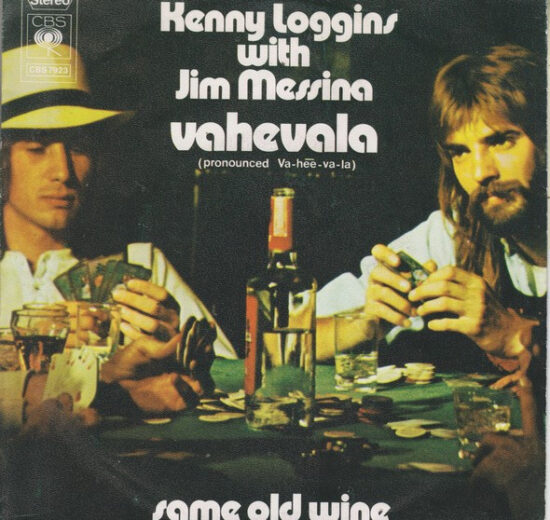 "Cover of the single 'Vahevala' by Kenny Loggins and Jim Messina, showing the duo sitting at a poker table with cards, drinks, and a bottle of wine." Description: "This is the cover art for the single 'Vahevala' by Kenny Loggins and Jim Messina. It depicts the duo seated at a poker table surrounded by cards, glasses, and a bottle of wine, capturing a relaxed and casual vibe. The text prominently displays the title 'Vahevala' with a pronunciation guide (Va-hee-va-la) and also includes the title of the B-side track, 'Same Old Wine.'"