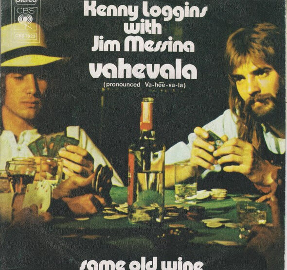 "Cover of the single 'Vahevala' by Kenny Loggins and Jim Messina, showing the duo sitting at a poker table with cards, drinks, and a bottle of wine." Description: "This is the cover art for the single 'Vahevala' by Kenny Loggins and Jim Messina. It depicts the duo seated at a poker table surrounded by cards, glasses, and a bottle of wine, capturing a relaxed and casual vibe. The text prominently displays the title 'Vahevala' with a pronunciation guide (Va-hee-va-la) and also includes the title of the B-side track, 'Same Old Wine.'"