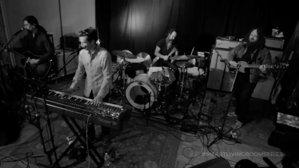 The Killers perform in a black-and-white setup for the iHeartRadio Living Room Concert Series, with Brandon Flowers on keyboard.