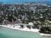 Aerial view of Key West, Florida, with turquoise waters, a sandy shoreline, tennis courts, and a dense collection of homes and buildings stretching inland.