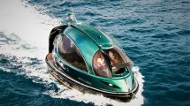 Futuristic green Jet Capsule mini-yacht cruising on open water with passengers visible inside