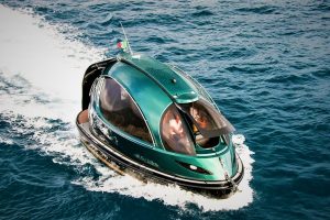Futuristic green Jet Capsule mini-yacht cruising on open water with passengers visible inside