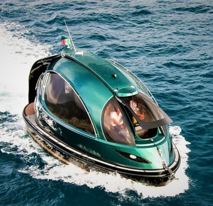 Futuristic green Jet Capsule mini-yacht cruising on open water with passengers visible inside