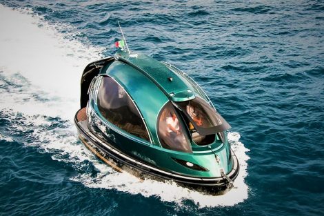 Futuristic green Jet Capsule mini-yacht cruising on open water with passengers visible inside