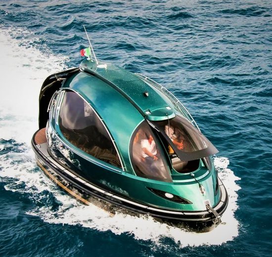 Futuristic green Jet Capsule mini-yacht cruising on open water with passengers visible inside