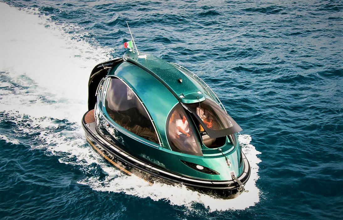 Futuristic green Jet Capsule mini-yacht cruising on open water with passengers visible inside
